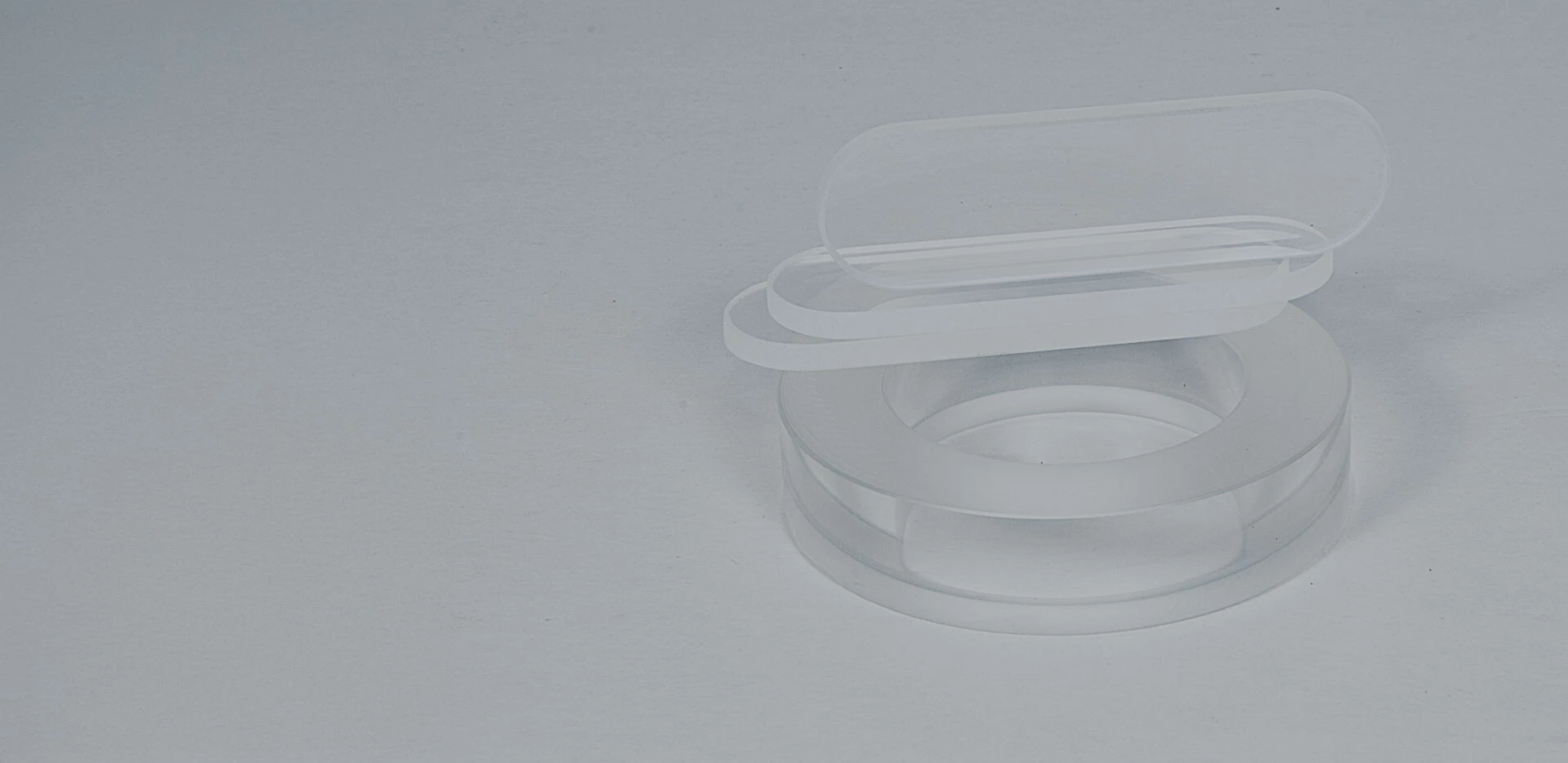 Eine transparente, runde Schale mit zwei flachen, klaren Deckeln.