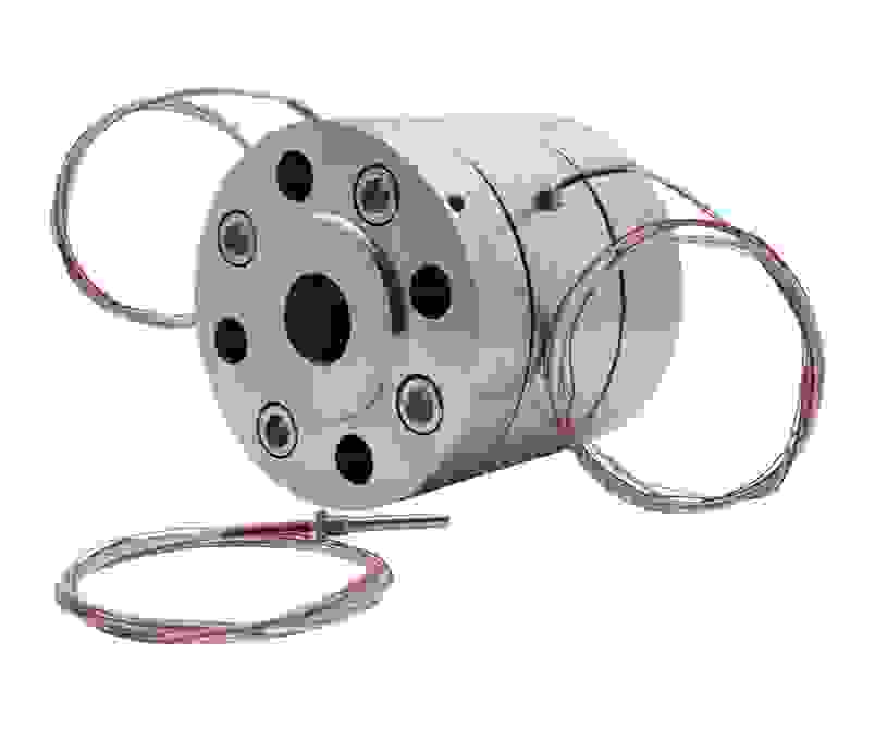 Ein metallisches Bauteil mit runder Form, mehreren Bohrungen und angeschlossenen Drähten. Es könnte sich um einen Sensor oder eine Verbindungseinheit handeln.