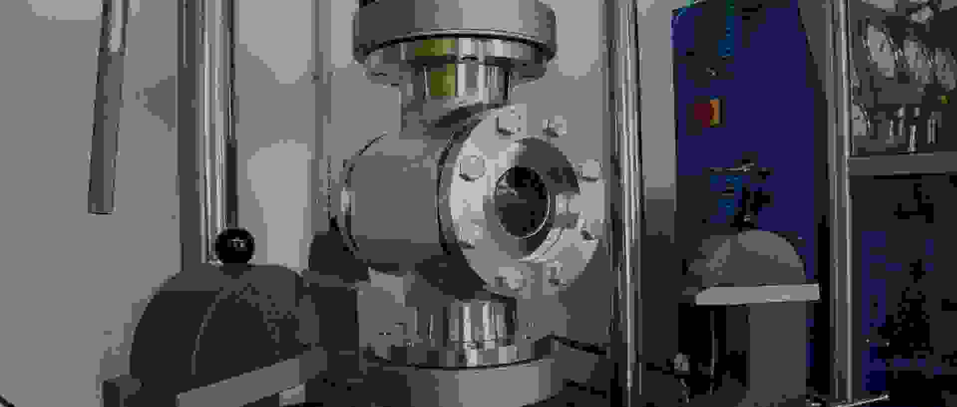 Ein industrielles Ventil aus Metall, umgeben von Maschinenkomponenten und Druckmessgeräten.