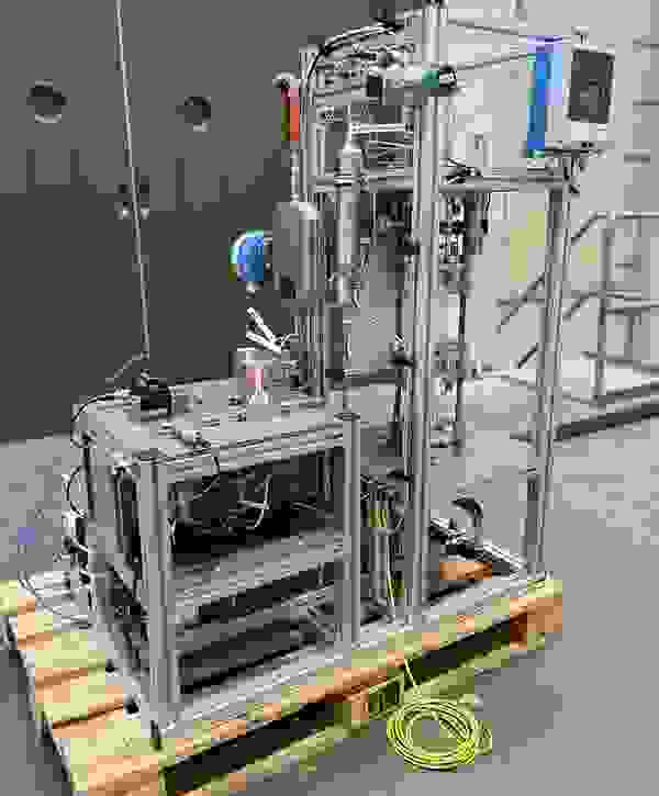 Technologische Vorrichtung mit Rohren, Messgeräten und Steuerungseinheiten auf einem Holzpalett.