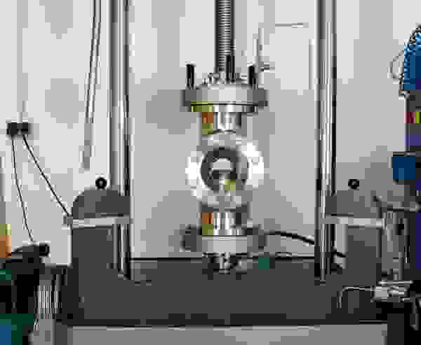 Eine industrielle Maschine mit einem Metallrahmen und einem zentralen Zylinder. Sie zeigt Druck- und Steuerungsmechanismen.