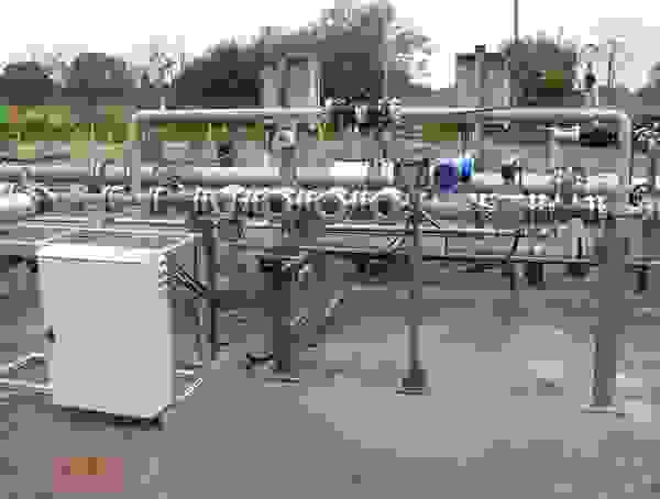 Pipeline-System mit Ventilen und Steuerungseinheit, umgeben von einer industriellen Umgebung.