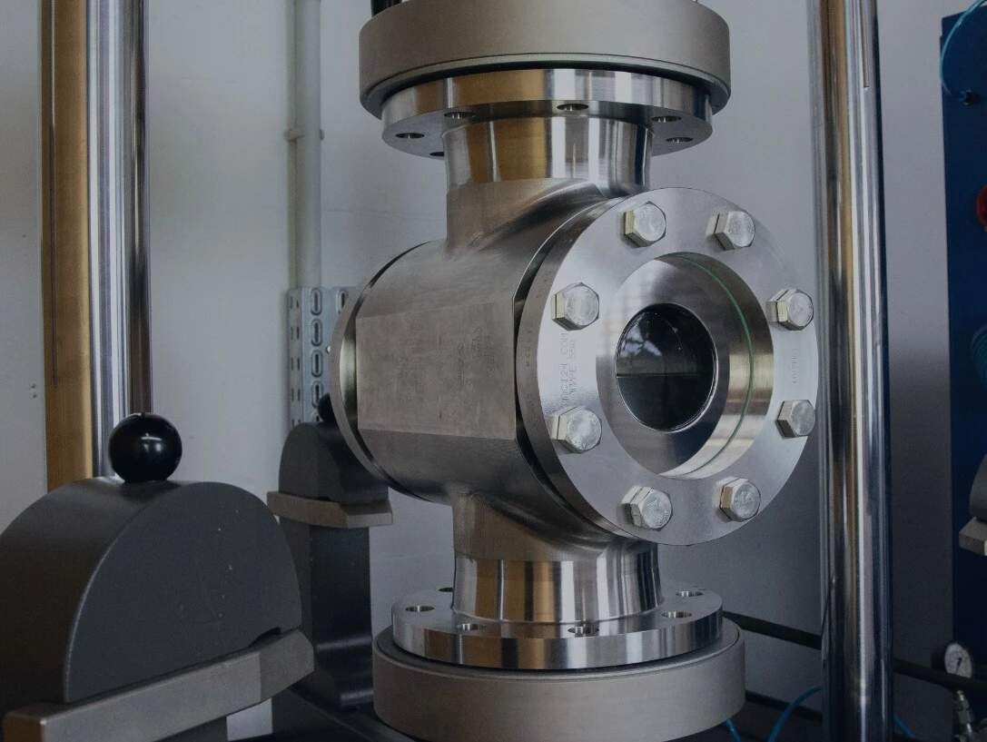 Ein industrielles Ventil aus Metall, umgeben von Maschinenkomponenten und Druckmessgeräten.