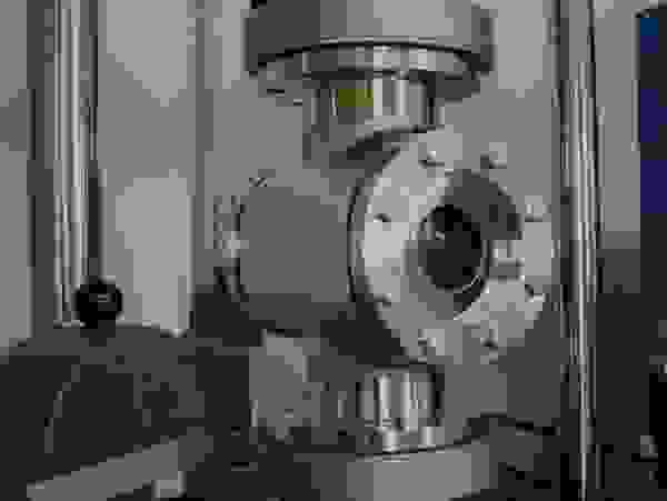 Ein industrielles Ventil aus Metall, umgeben von Maschinenkomponenten und Druckmessgeräten.
