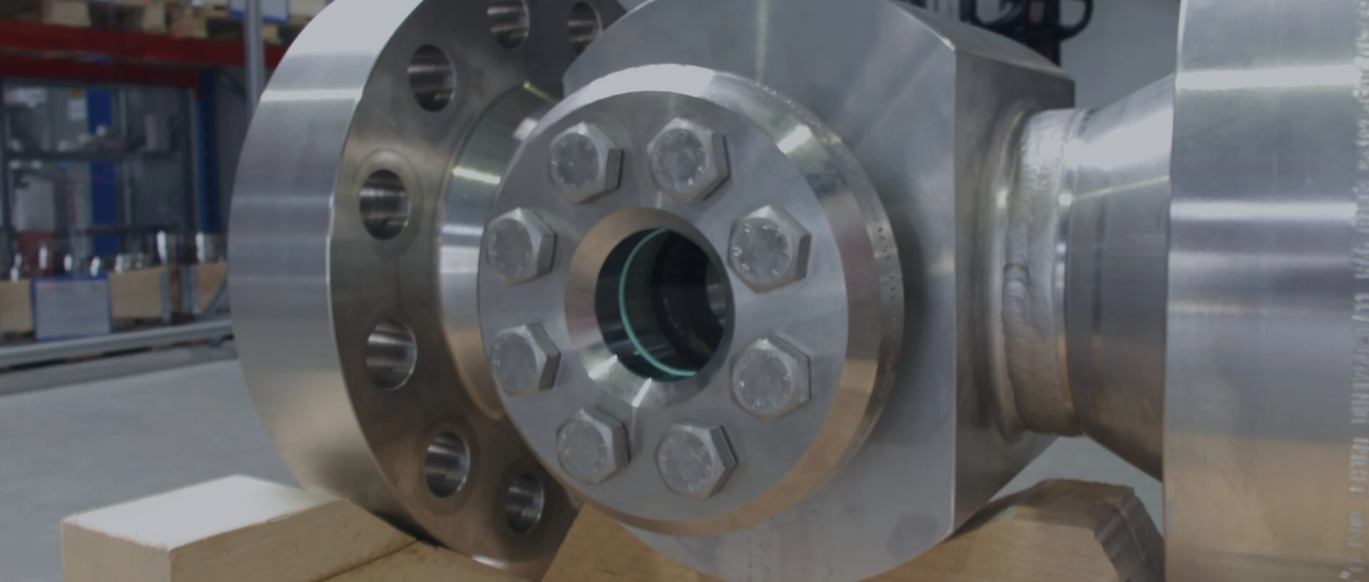 Close-up of a shiny metal flange with hex bolts on a wooden surface.