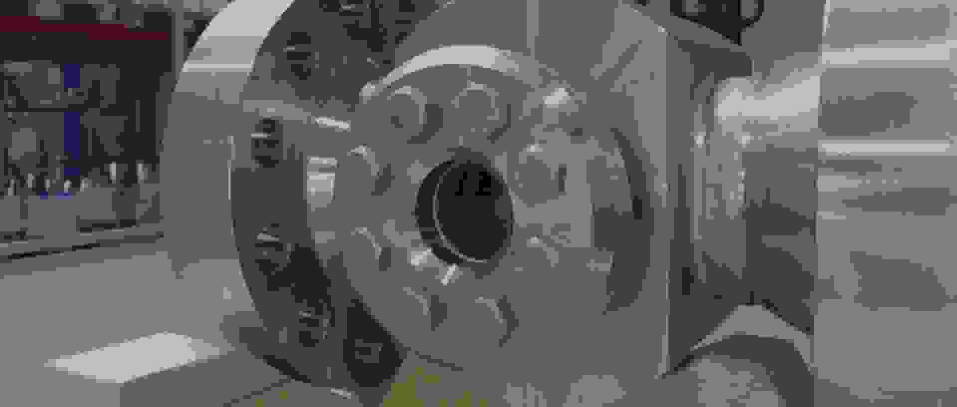 Close-up of a shiny metal flange with hex bolts on a wooden surface.
