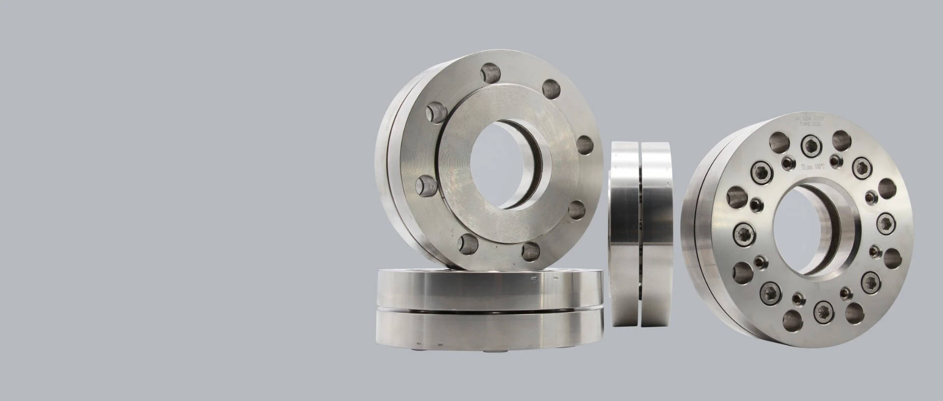 Stainless steel machine parts, including various pulleys and flanges, on a grey background.