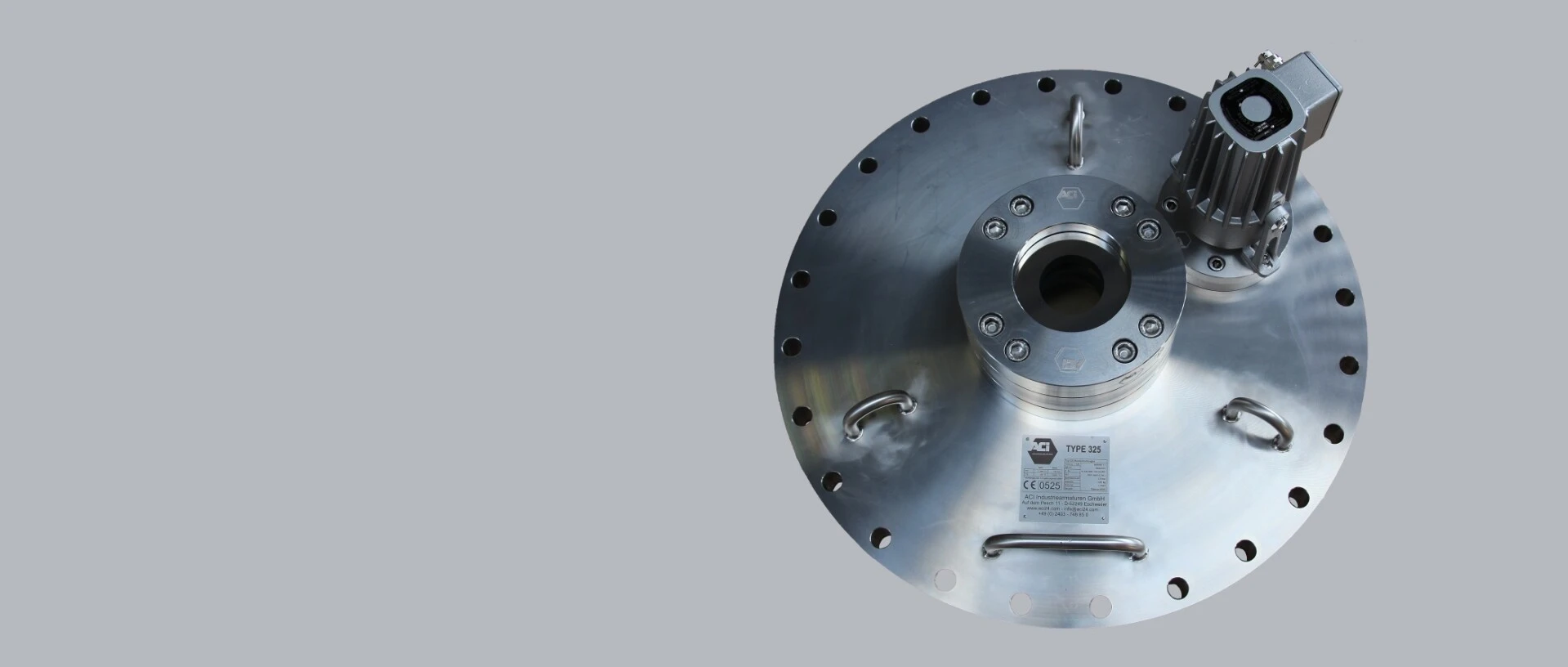 A metallic plate with a central hole, bolts, and a small motor device on top.