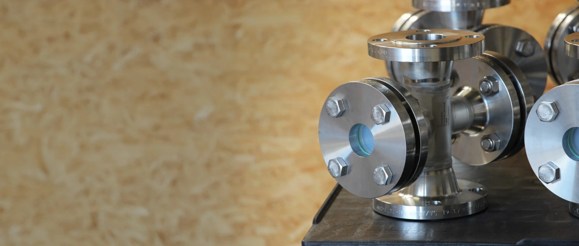 Stainless steel flanges and pipe fittings on a table, with a bright background.