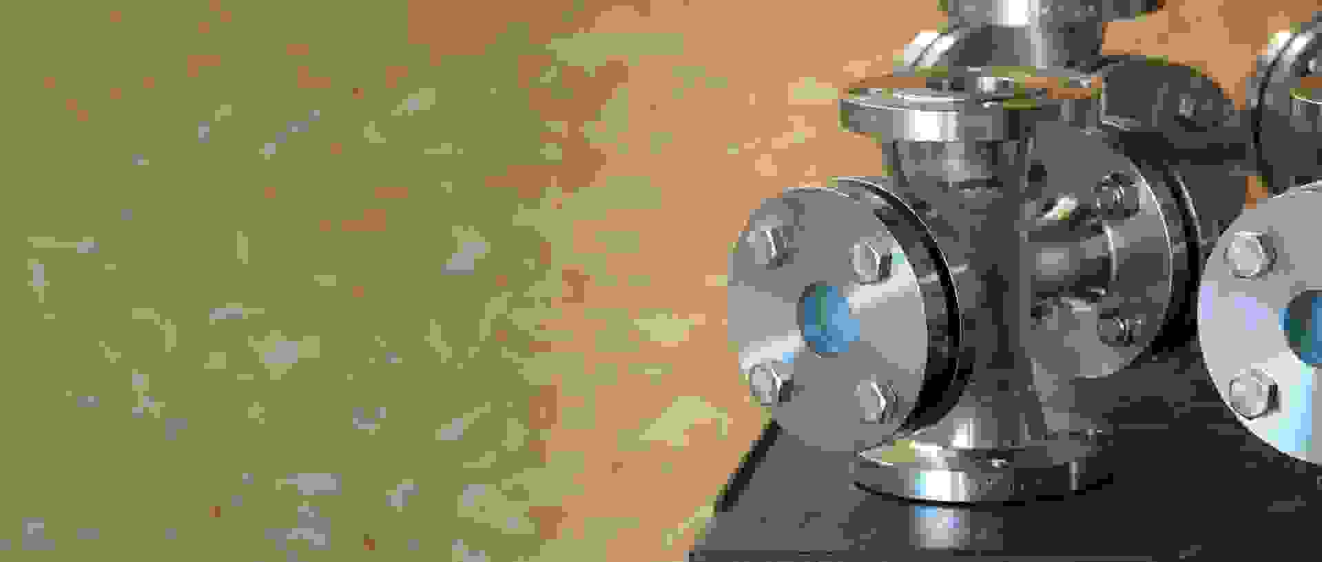 Stainless steel flanges and pipe fittings on a table, with a bright background.