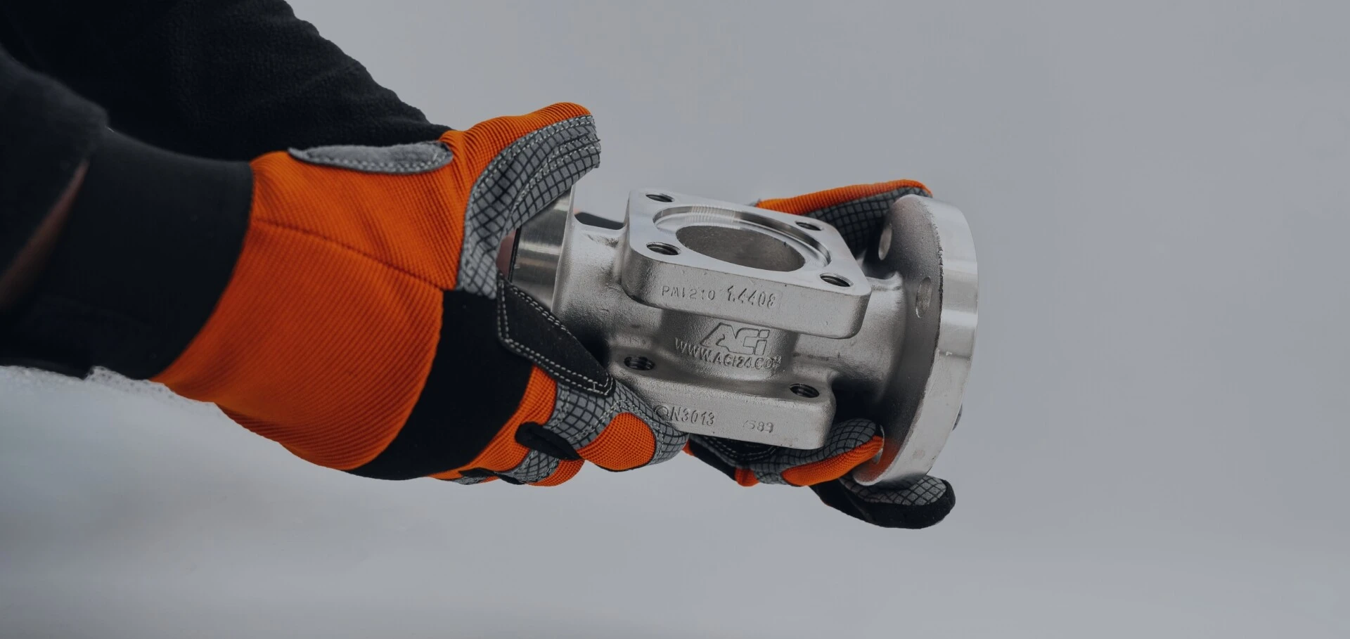 Someone is holding a custom-made fitting from ACI in their hands, wearing gloves.