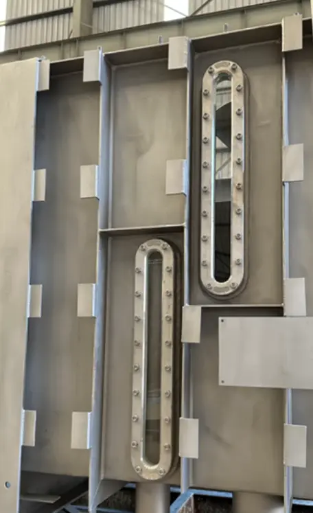 Metallische Struktur mit zwei ovalen Fenstern, die mit Bolzen befestigt sind.