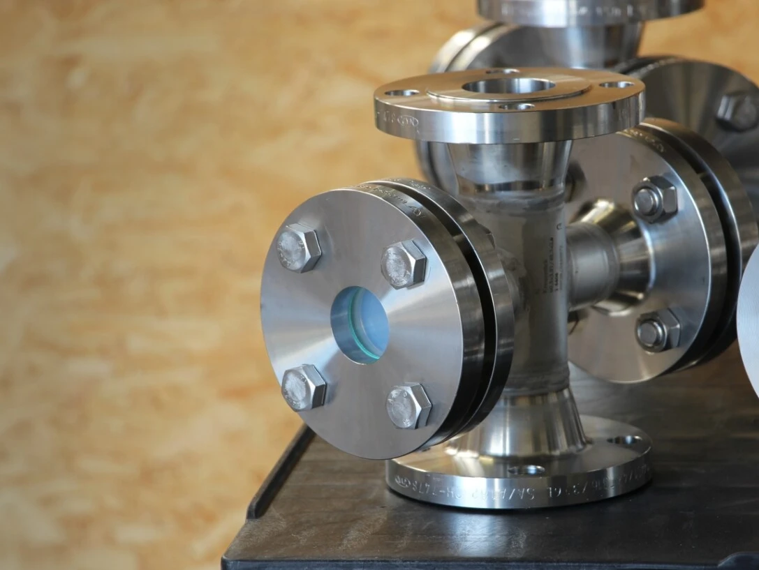 Stainless steel flanges and pipe fittings on a table, with a bright background.