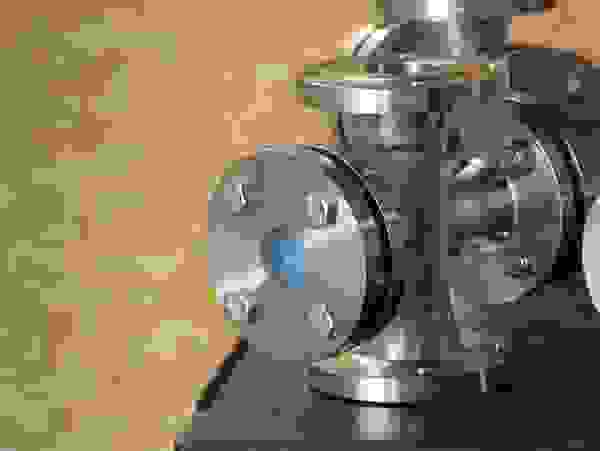 Stainless steel flanges and pipe fittings on a table, with a bright background.