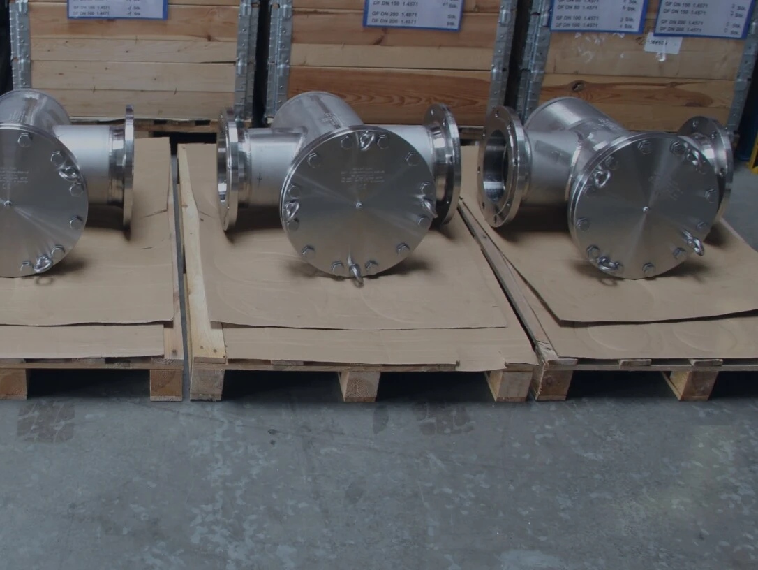 Several stainless steel components in a warehouse, placed on wooden pallets.