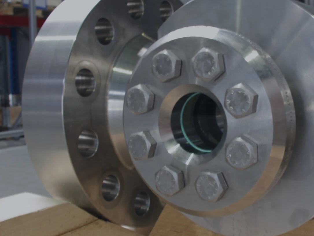 Close-up of a shiny metal flange with hex bolts on a wooden surface.