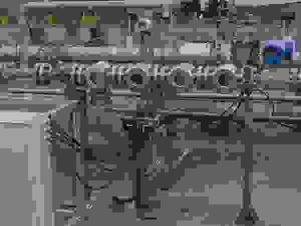 Several metal pipes and valves that are part of an industrial piping system, with a control box in the foreground.