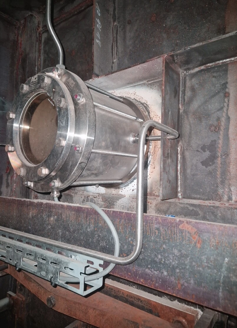 Tube en acier inoxydable avec conduites de raccordement, monté sur une structure métallique.