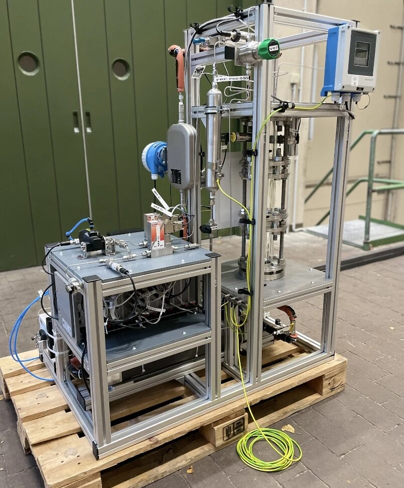 Dispositif technologique avec des tuyaux, des appareils de mesure et des unités de commande sur une palette en bois.