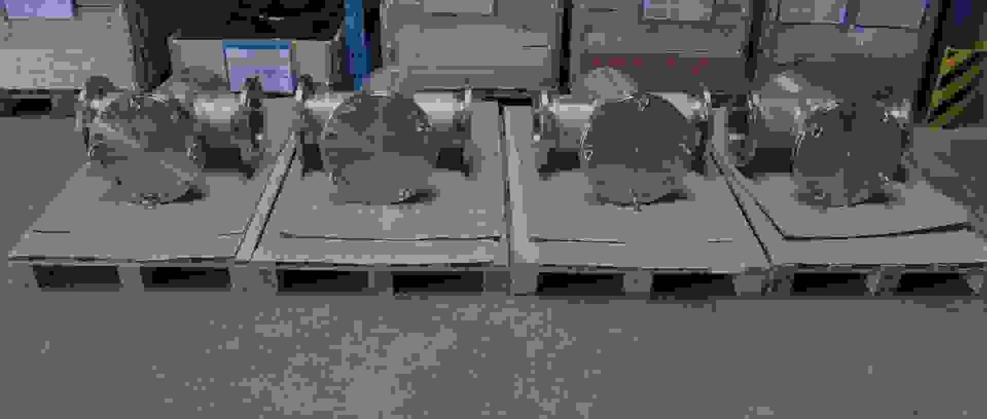 Meerdere roestvrijstalen componenten in een magazijn, op houten pallets geplaatst.
