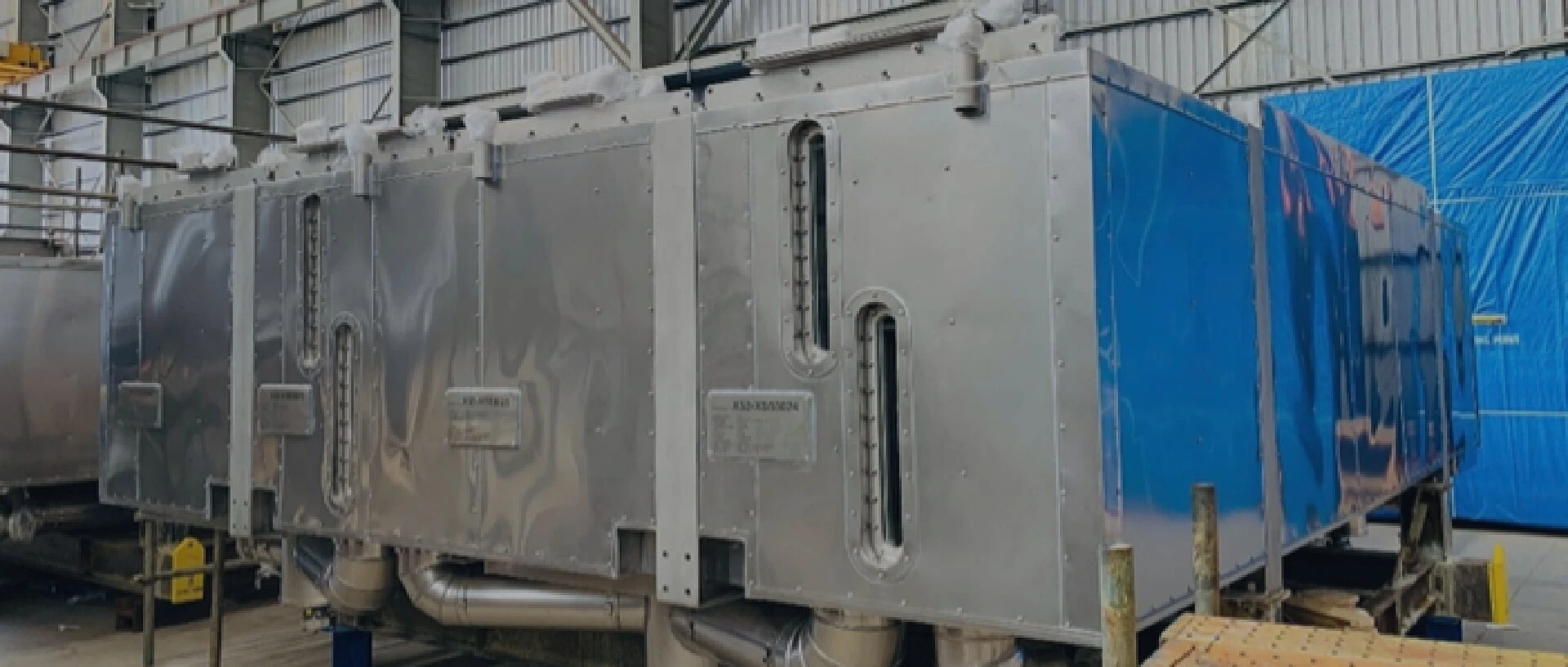 Een grote, glanzende metalen constructie met buizen die in een opslagruimte staat.