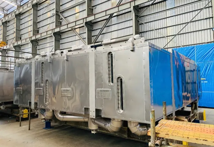 Groot industrieel metalen apparaat met een zilveren en blauwe kleur, opgeslagen in een hal.