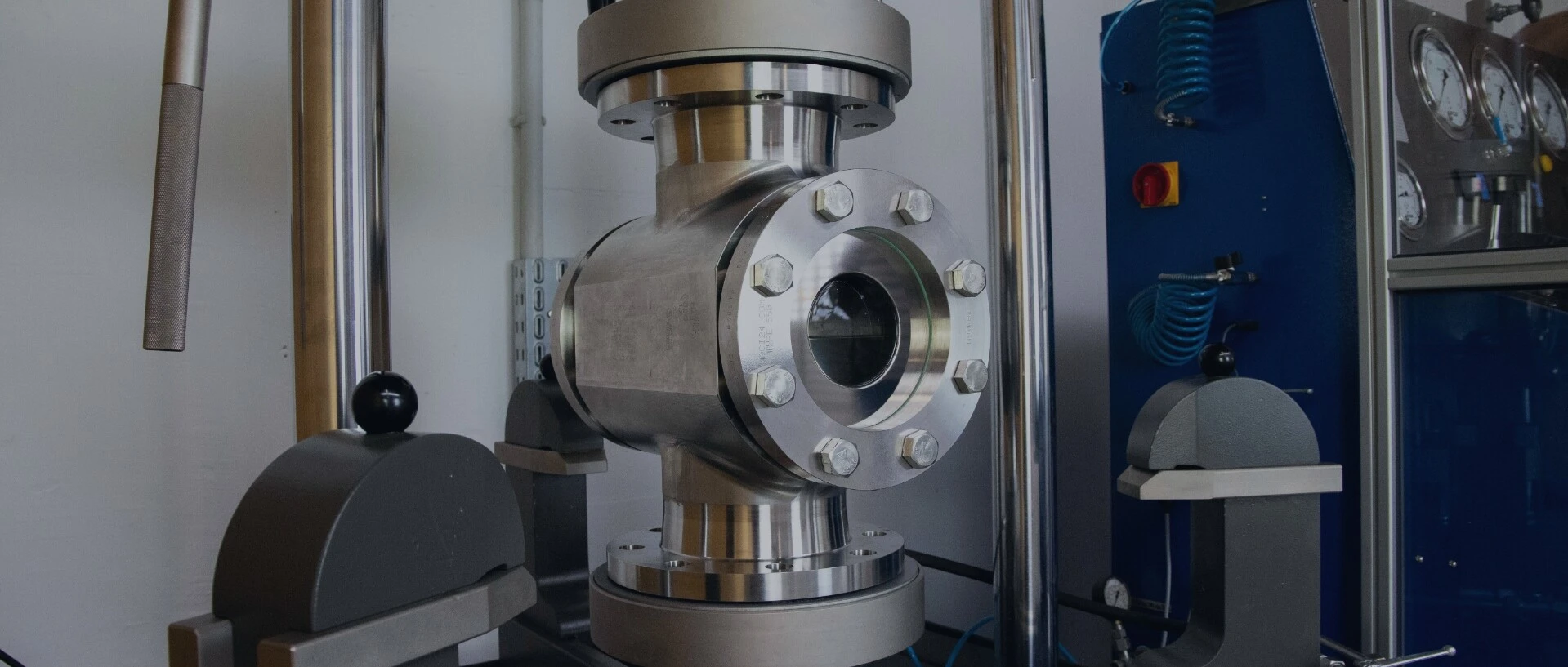 Een industrieel metalen ventiel, omgeven door machinecomponenten en drukmeetapparatuur.