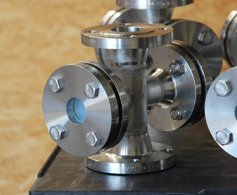 Zawór ze stali nierdzewnej z kołnierzami i śrubami, umieszczony na stole.